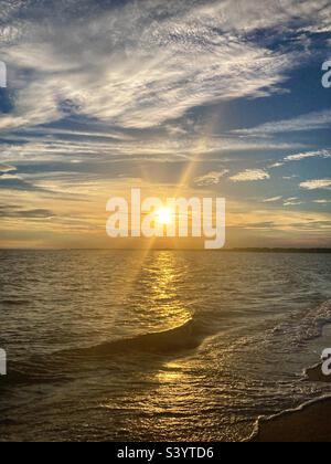 Sunset over the Long Island Sound with sun rays bursting out on a beautiful, beach day Stock Photo