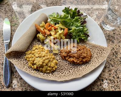 Ethiopian food YE'KIKI ALICHA (split chickpeas) YE'MISIR WAT (spicy lentils) and YE'ATAKELT ALICHA (cabbage with carrots) on gluten free Teff Injera bread Stock Photo