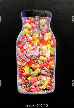 A large jar of traditional and colourful boiled sweets or candy on a black background Stock Photo