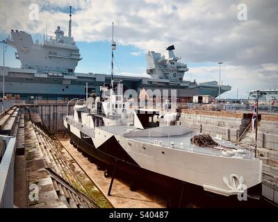 HMS Queen Elizabeth aircraft carrier docked at Portsmouth Historic Dockyard, and HMS M33 on display in front, summer 2022 Stock Photo