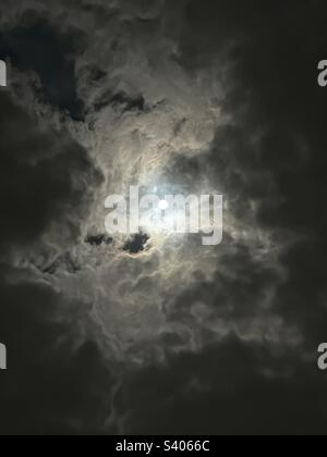 Black-and-white photo of a full moon shining through the clouds Stock Photo