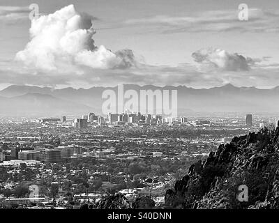 Phoenix skyline viewed from rocky slopes of Phoenix Mountain Preserve, Arizona, fluffy white clouds gathering and turning grey over South Mountain, black and white Stock Photo