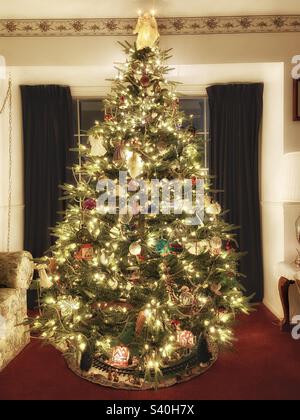A beautiful artificial fir Christmas tree alighted with white lights. The tree fills this Utah home with a soft radiant glow of Christmas cheer and goodwill. Stock Photo