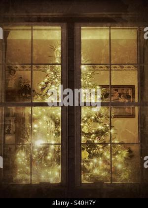 A beautiful artificial fir Christmas tree alighted with white lights as seen from the outside of this Utah home. IOS app Snapseed was used to give the image a vintage and grunge texture  and look. Stock Photo