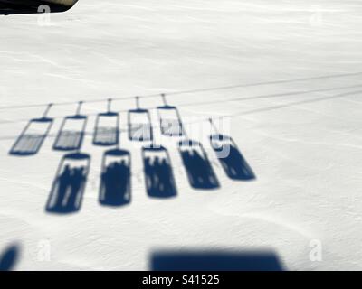 Shadows of bucket lifts on fresh snow taking people up to the ski slopes, Alpe d’Huez. Stock Photo