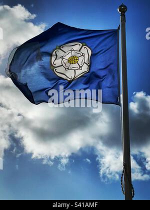 ‘Yorkshire’ the white rose flag of the county of Yorkshire catches the wind on a day where the sky matches its colours. Stock Photo