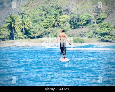 A man rides a foil board on the water near Santa Teressa in Costa Rica Stock Photo