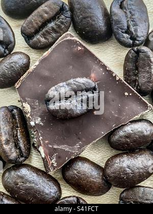 Closeup of dark roasted coffee beans with a piece of almond chocolate. Stock Photo
