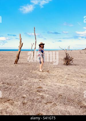 A beautiful woman poses in front of interesting driftwood on Lo De Marcos beach. Stock Photo