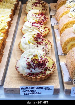 White chocolate pistachio raspberry tart in bakery window Stock Photo