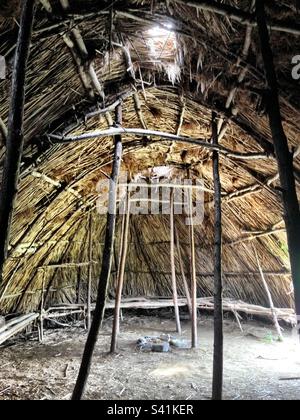 Harvard, Massachusetts, USA: inside Native American shelter mades of wood and sticks at Fruitlands Museum. Light pouring in from different openings. Stock Photo