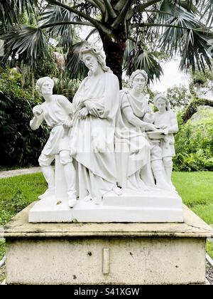 Stations of the cross, 1st station, Jesus condemned, white nearly life-size statues, raised platform, dwarfed by Palm tree, expressions fear, resolute, regret, curiosity Stock Photo