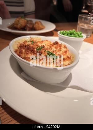 Salmon, smoked haddock and prawn encrusted pjie with minted peas Stock Photo