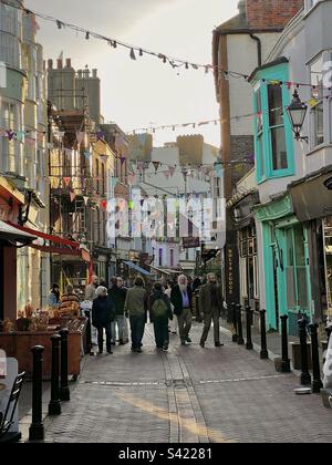 Pedestrians shopping and browsing on George street in Hastings Old town, at sunset, East Sussex, England Stock Photo