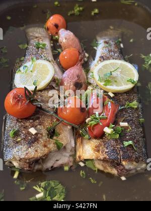 Seabass baked in oven with lemon, garlic and cherry tomatoes Stock Photo