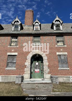 Abandoned, red brick building with green door with sign that says private property, no trespassing. At Seaside State Park in Waterford, Connecticut, USA. It was a former medical facility. Stock Photo