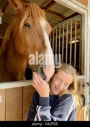 Teenage girl daughter makes a funny face posing with a beautiful horse Stock Photo