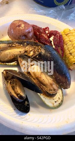 Black and green mussels, with a potato, corn, cob, and crawfish on a plate Stock Photo