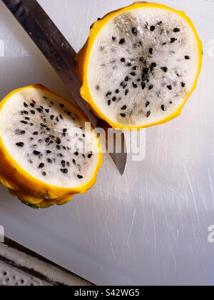 Close-up of a honey dragon fruit sliced into with a paring knife on a cutting board, 2023, USA Stock Photo