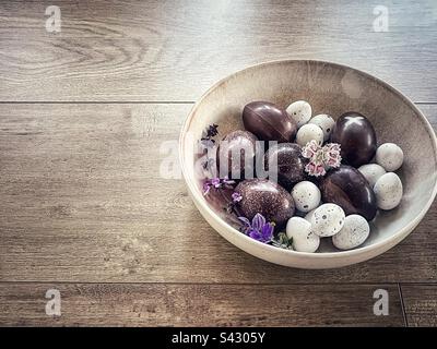 Easter chocolate and praline eggs in bowl on wooden table. Stock Photo