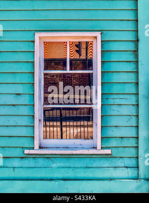 Close up abstract of street reflection in a single, closed window of blue, wooden facade. Stock Photo