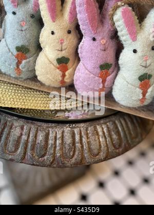Four small pastel stuffed Easter Bunnys standing in a line holding carrots. Includes print space. Stock Photo