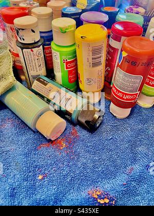 Colorful artist’s paint set on messy paint splattered blue textured drop cloth. Includes print space. Stock Photo