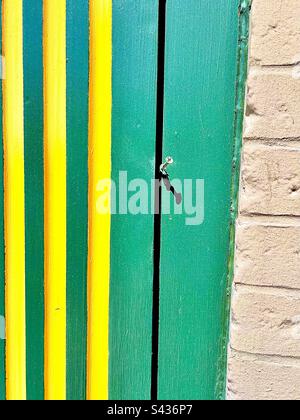 Green wooden wall with three yellow vertical stripes meets white brick wall near right side. Includes print space. Stock Photo