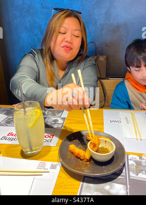 A lady enjoying a squid starter in a restaurant Stock Photo
