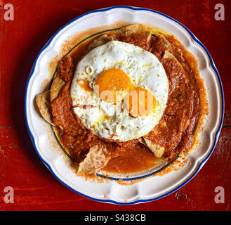 Chilaquiles with red tomatoe sauce with two fried eggs in Mexico Stock Photo