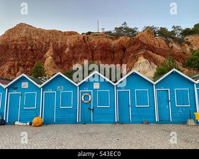 Blue wooden boat garages in front of sandstone rocks in Olhos de Água in Algarve, Portugal. Stock Photo