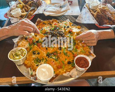 Two people sharing a giant plate of nachos. Stock Photo