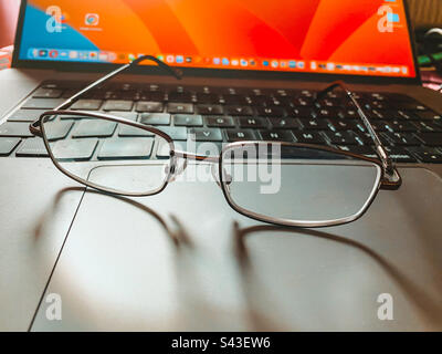 A pair of reading glasses on a laptop keyboard. Stock Photo