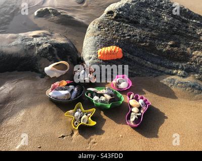 Beach toys filled with shells and stones on the sand. Stock Photo