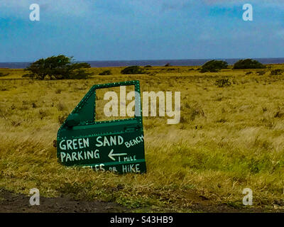 A painted sign for Papakōlea Beach, a green sand beach located on the Big Island of Hawaii. The sign is made from a car door. Stock Photo