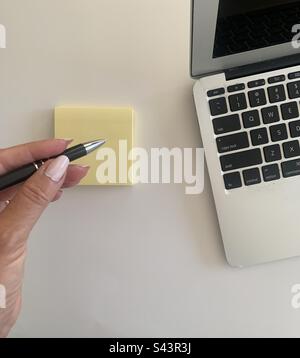 Woman with a pen in her hand making notes next to her portable computer Stock Photo