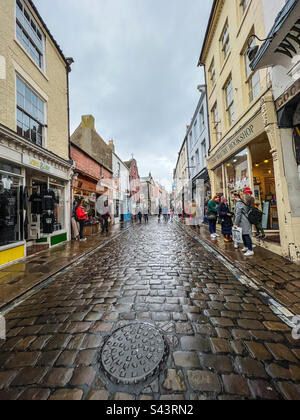 Shoppers on cobblestone streets at Church Street in Whitby North Yorkshire Stock Photo