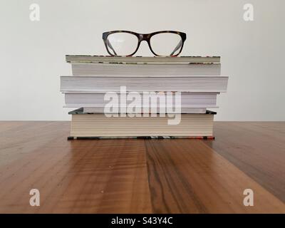 Closeup image of a pile of books on a wooden table against a white background Stock Photo
