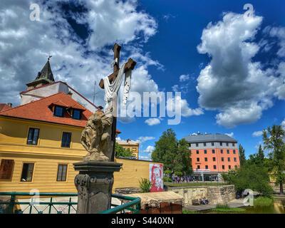 Big cross stone statue with white clouds and blue sky in the historical center of Pilsen, Czech Republic. Stock Photo