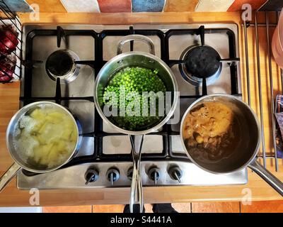 Three saucepans cooking food on a gas hob. Stock Photo