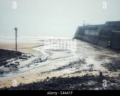 Porthcawl breakwater and Trecco Bay at low tide, misty drizzle day, Porthcawl, South Wales. Stock Photo