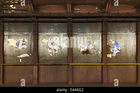Peeling paint on a subway wall revealing signs underneath Stock Photo