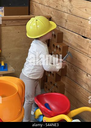 Educational - measuring wood on a pretend building site - young boy wearing a hard hat Stock Photo