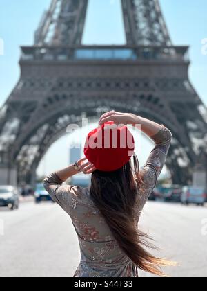 Young woman wearing red beret in Paris in front of Eiffel Tower Stock Photo