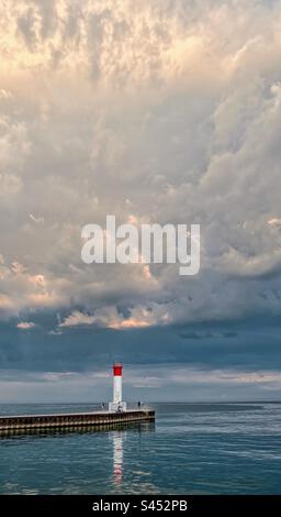 Lighthouse at end of pier with dramatic storm clouds above. Lake Ontario, Canada. Stock Photo