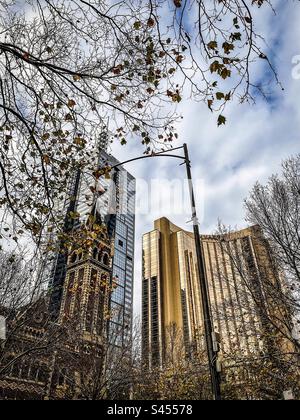 Low angle view of Hyatt Hotel and St.Michael’s Uniting Church in Collins Street in central Melbourne with autumn leaf foliage. Juxtaposition. Old vs new. Stock Photo