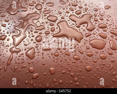 Droplets of water on a shiny brown surface after a rain shower. Backgrounds. Stock Photo