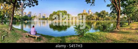 Panoramic of man sitting on a bench in Lumpini park Bangkok Thailand Stock Photo