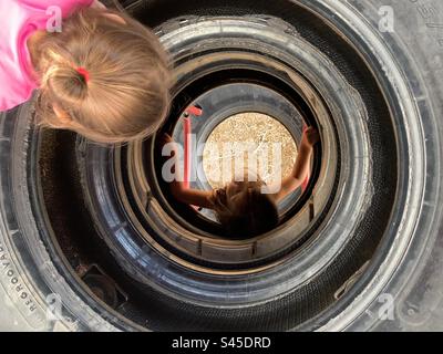 Two little girl playing on playground tire ladder. Stock Photo