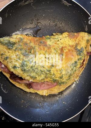 Omelette with herbs and cheese, stuffed with crispy bacon. Stock Photo